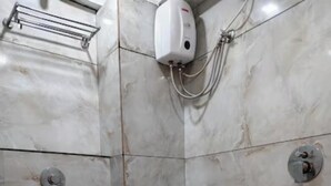 Ein Badezimmer mit Toilette, Handtrockner, Dusche und zwei Eimern.