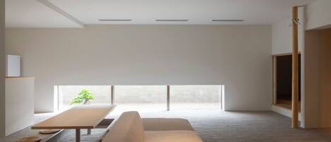 Una habitación minimalista con un ventanal grande, un sofá, una mesa y un televisor.