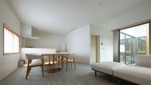 Una moderna camera d'albergo con zona pranzo, divano e un'ampia finestra.