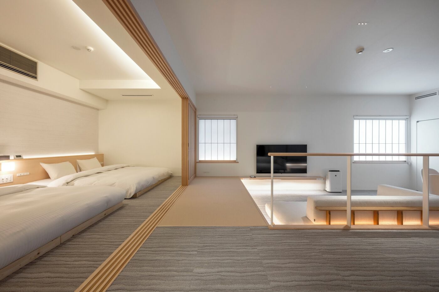 A modern hotel room with a large bed, a seating area, a TV, and a fireplace.
