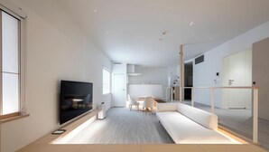 Un soggiorno moderno con divano, televisione e zona pranzo.