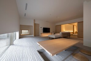 A modern hotel room with a large bed, a seating area, a TV, and a sliding door leading to another room. - JINRYU HOTEL ISE (Ise)