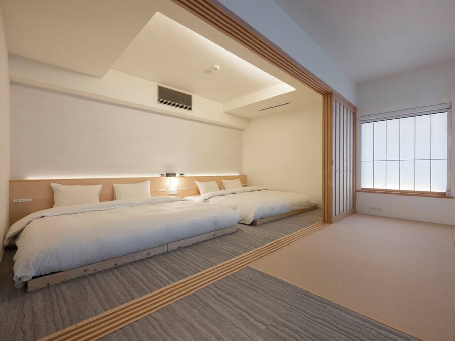 Una habitación de hotel moderna con dos camas, un tragaluz, un ventanal grande y un diseño minimalista.