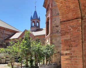 A historic building with a bell tower, brick walls, and trees in the foreground. - Designer Studio Beneath Historic Vaulted Ceilings (Grossharthau)