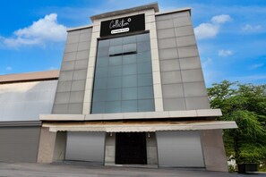 A modern building with a large glass facade, a sign reading 'Collection,' and a metal door at the entrance. - Deluxe Hotel Koshalya Mohan (Jabalpur)