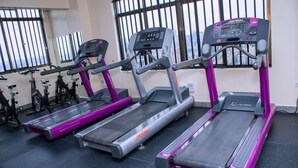 Tre løbebånd i et fitnesscenter med udsigt over byen gennem vinduet.