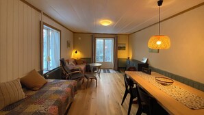 Una habitació acollidora amb terra de fusta, un sofà, una taula de menjador i una cadira.