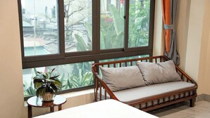 A room with a wooden bench, a potted plant, and a view through large windows. - An's Home Ninh Binh (Ninh Binh)