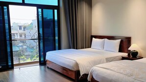 A hotel room with two beds, a large sliding glass door, and a view of buildings outside. - An's Home Ninh Binh (Ninh Binh)