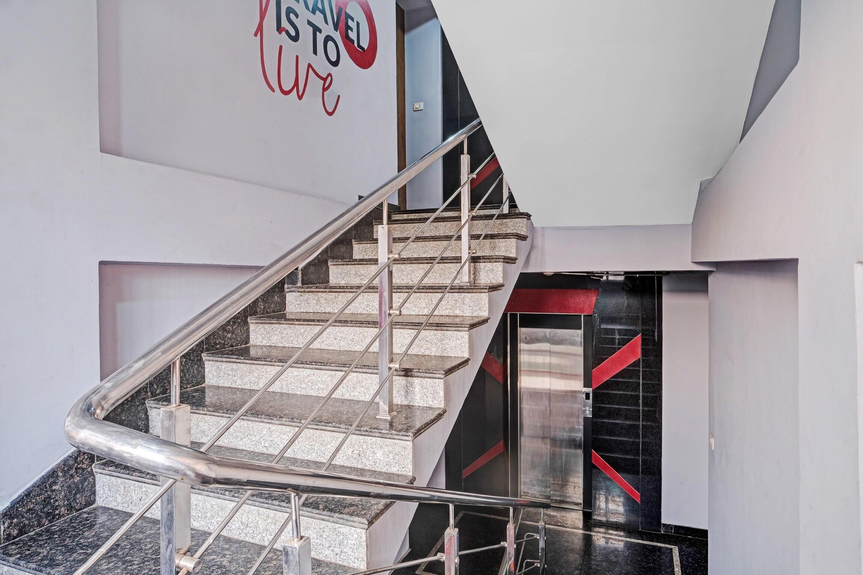 A modern staircase with metal railings, leading to a room with a black and red accent wall.
