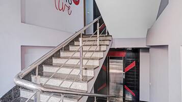 A modern staircase with metal railings, leading to a room with a black and red accent wall.