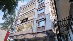 A multi-story building with balconies, a sign reading 'TOM HOUSE,' and a covered outdoor area. - Classic With Balcony Luxuria Ganeshguri (Guwahati)