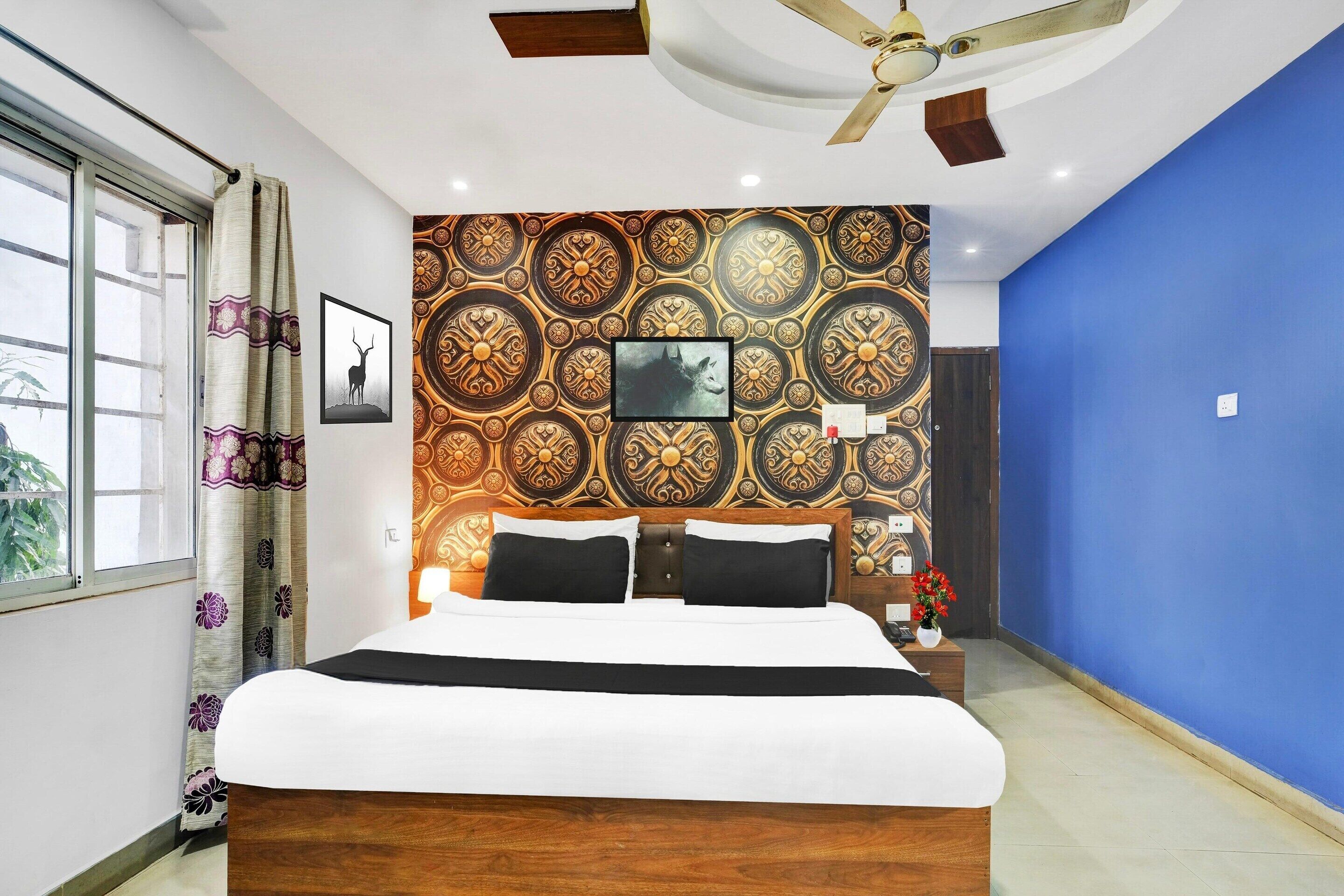A bedroom with a bed, a ceiling fan, patterned wallpaper, and a blue wall.