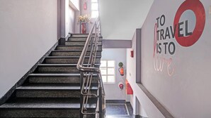 A staircase with metal railings, a wall with 'TO TRAVEL' text, and a window with a plant. - Classic With Balcony Luxuria Ganeshguri (Guwahati)