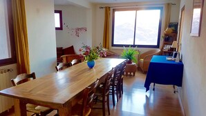 A dining area with a wooden table, chairs, a blue tablecloth, and a potted plant. - LA MAISON DE JOSEPHINE  (Risoul)