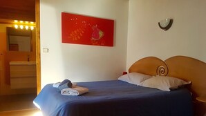 A bedroom with a bed, a red artwork, a nightstand, and a wooden headboard. - LA MAISON DE JOSEPHINE  (Risoul)