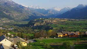 A mountain village with traditional houses, a winding road, and snow-capped peaks in the background. - LA MAISON DE JOSEPHINE  (Risoul)