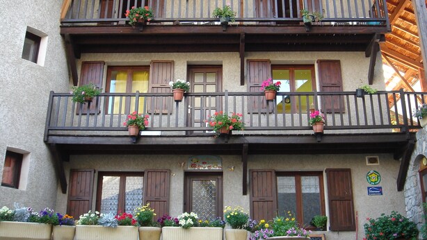 A multi-story building with balconies, wooden shutters, and flower planters. - LA MAISON DE JOSEPHINE  (Risoul)