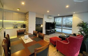 A modern living room with a dining area, a kitchen, and a large sliding glass door to the outdoors. - Terrace On Rose 2B2B 173m2 Pool Sauna/Steam Spa Room Gym FREE Secure Parking (Melbourne)