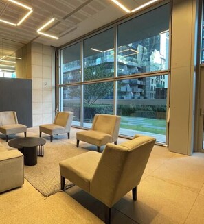 A modern interior with large windows, a seating area with sofas and a coffee table, and a view of a building outside. - Terrace On Rose 2B2B 173m2 Pool Sauna/Steam Spa Room Gym FREE Secure Parking (Melbourne)