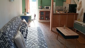 Una sala de estar con sofá, una mesa de comedor, un área de cocina y una escalera.