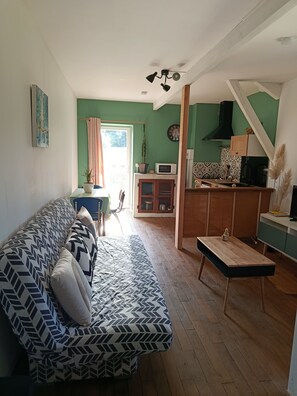Ein Wohnzimmer mit Sofa, Esstisch, Küchenzeile und Treppe.