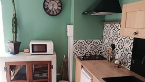 Una cocina con microondas, armarios, un lavabo, una estufa, un reloj y una planta en maceta.