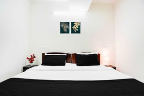 Une chambre d’hôtel comprenant un lit, une table de chevet, une lampe et deux œuvres d’art murales.