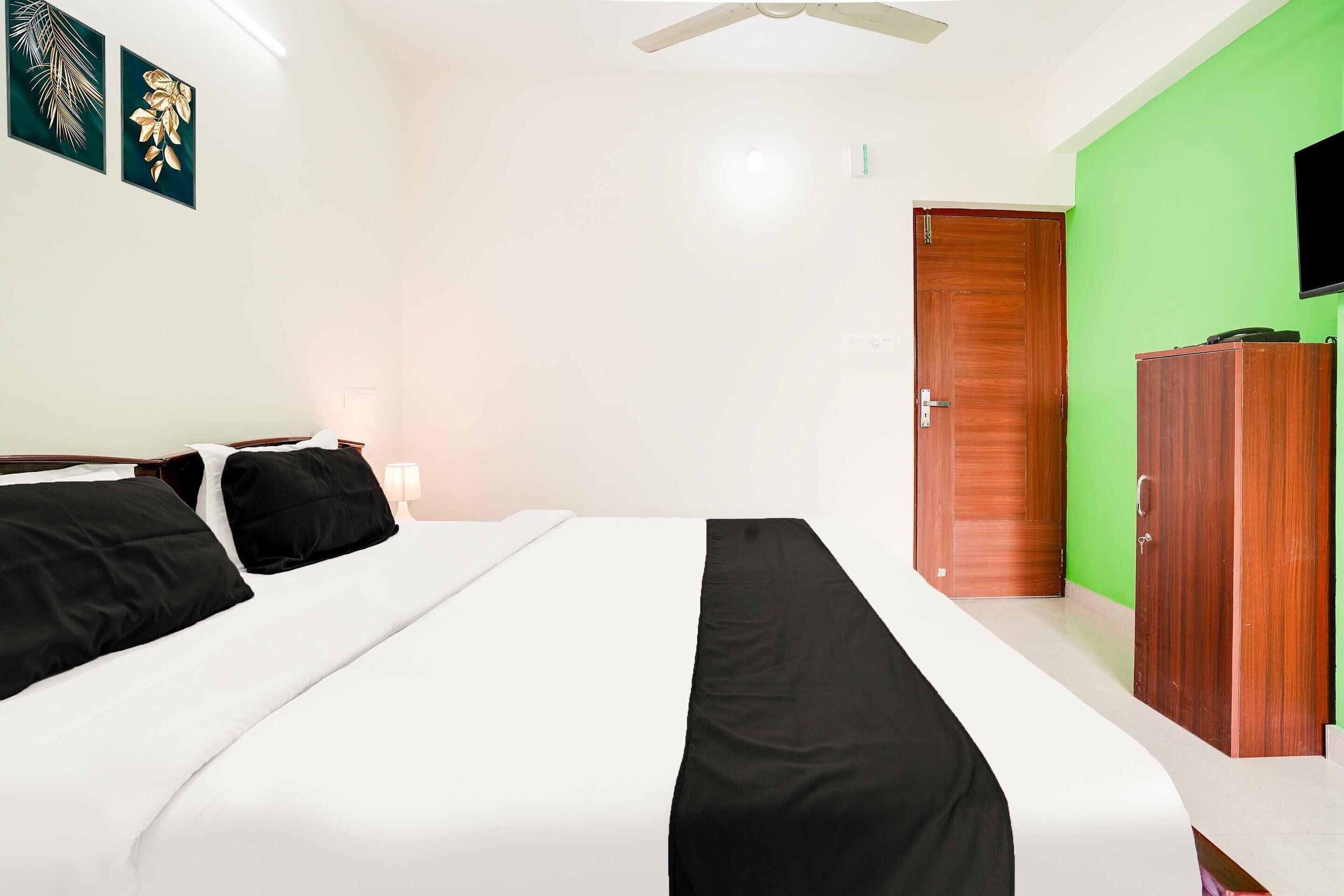 A hotel room with a bed, a wardrobe, a television, and a green wall.