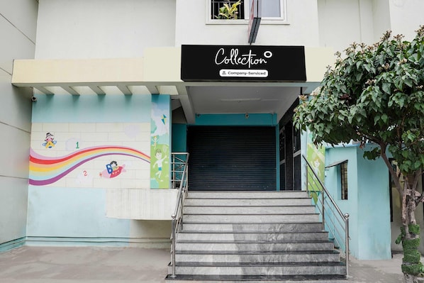 Une entrée d’immeuble avec un escalier, une fresque murale et une enseigne indiquant « Entreprise de recouvrement de créances ».