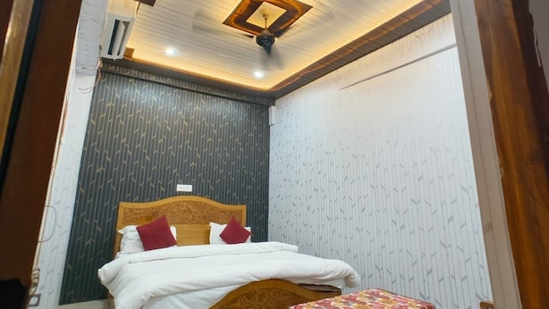 Un dormitorio con una cama, una mesita de noche, una lámpara de techo y una puerta.