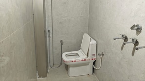 Un baño pequeño y cerrado con inodoro, ducha y barra de apoyo.