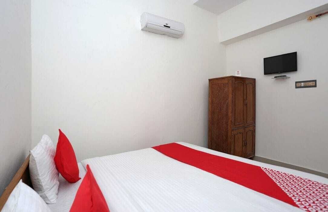 A bedroom with a bed, a wardrobe, a television, and an air conditioning unit.
