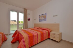 Ein Schlafzimmer mit einem Bett, einem Nachttisch, einer Schiebetür und einer Wandleuchte.