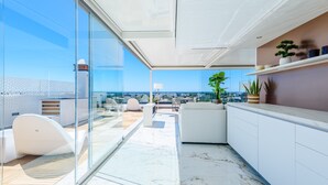 Ein modernes Interieur mit Glaswand, weißen Möbeln und Blick auf die Stadt.