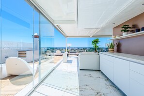 Ein modernes Interieur mit Glaswand, weißen Möbeln und Blick auf die Stadt.