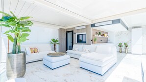 Ein modernes Wohnzimmer mit einem weißen Sofa, einem Couchtisch und einer großen Kübelpflanze.