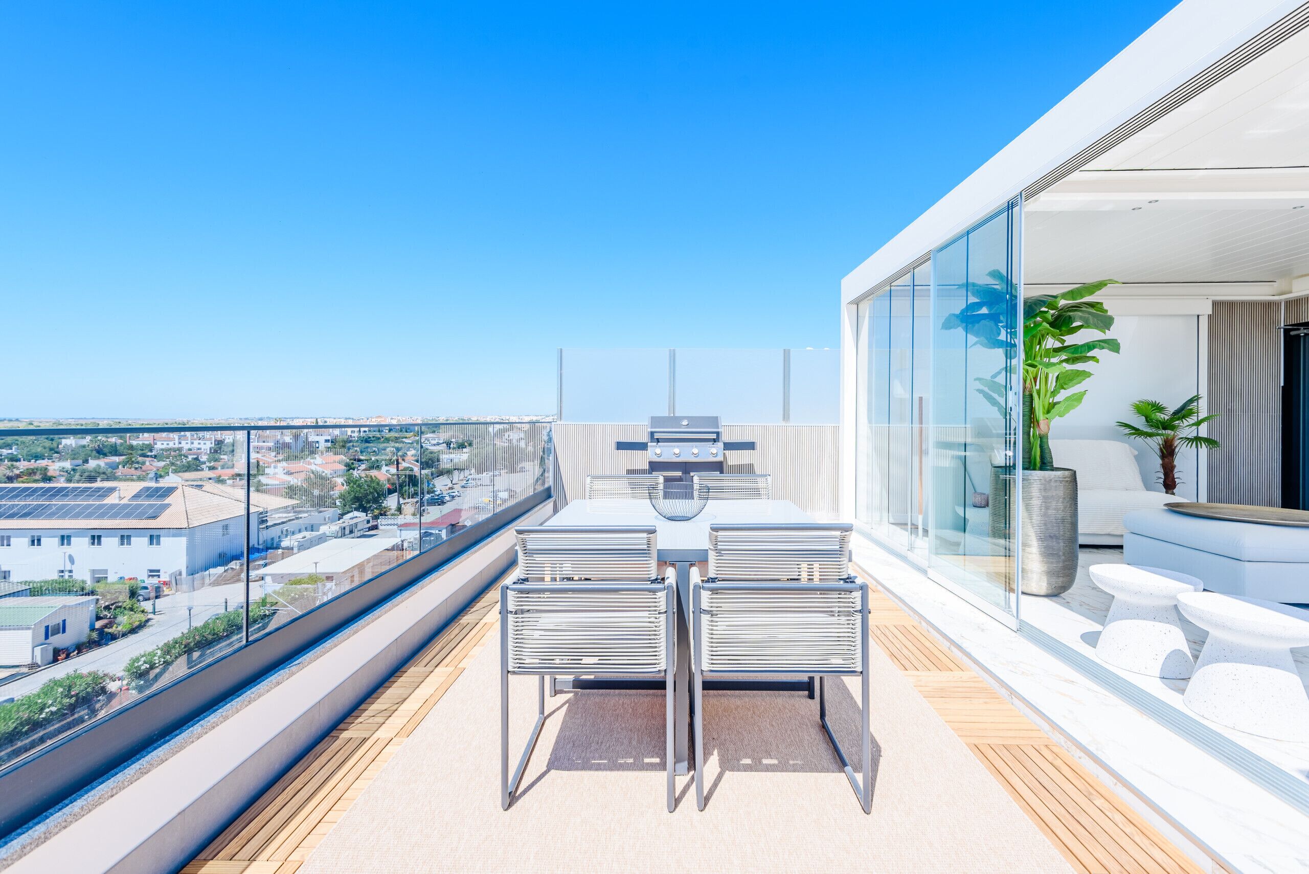 Ein Balkon mit Tisch und Stühlen, einem Blumentopf und Blick auf die Stadt.