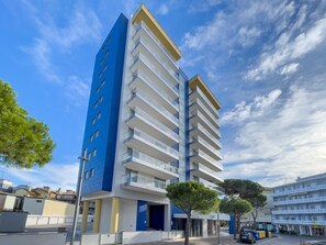 Un edificio moderno a più piani con balconi, una combinazione di colori blu e bianco e cielo sereno.