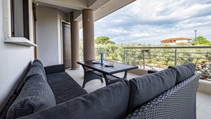 Ein Balkon mit einer Couch, einem Tisch und einem Stuhl.
