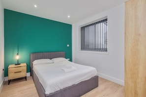 A bedroom with a bed, nightstand, and window with blinds. - Etna House (Birmingham)