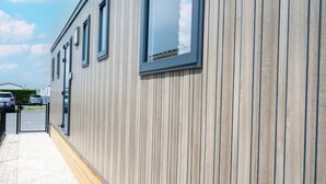 Ein Gebäude mit Holzwand, befestigtem Eingangsbereich und mehreren Fenstern.