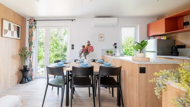 Eine moderne Küche mit Essbereich, Holzschränken und einem großen Fenster.