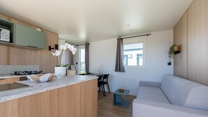 A modern kitchen with a central island, a dining area with a table and chairs, and a living area with a sofa.