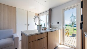 A modern kitchen with a built-in island, a sliding glass door to a deck, and a light-colored sofa.