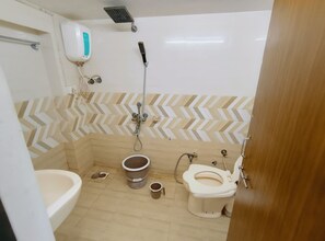 Un baño pequeño con ducha, inodoro y lavamanos.