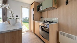 Eine moderne Küche mit Holzschränken, einer eingebauten Mikrowelle und einem Gasherd.