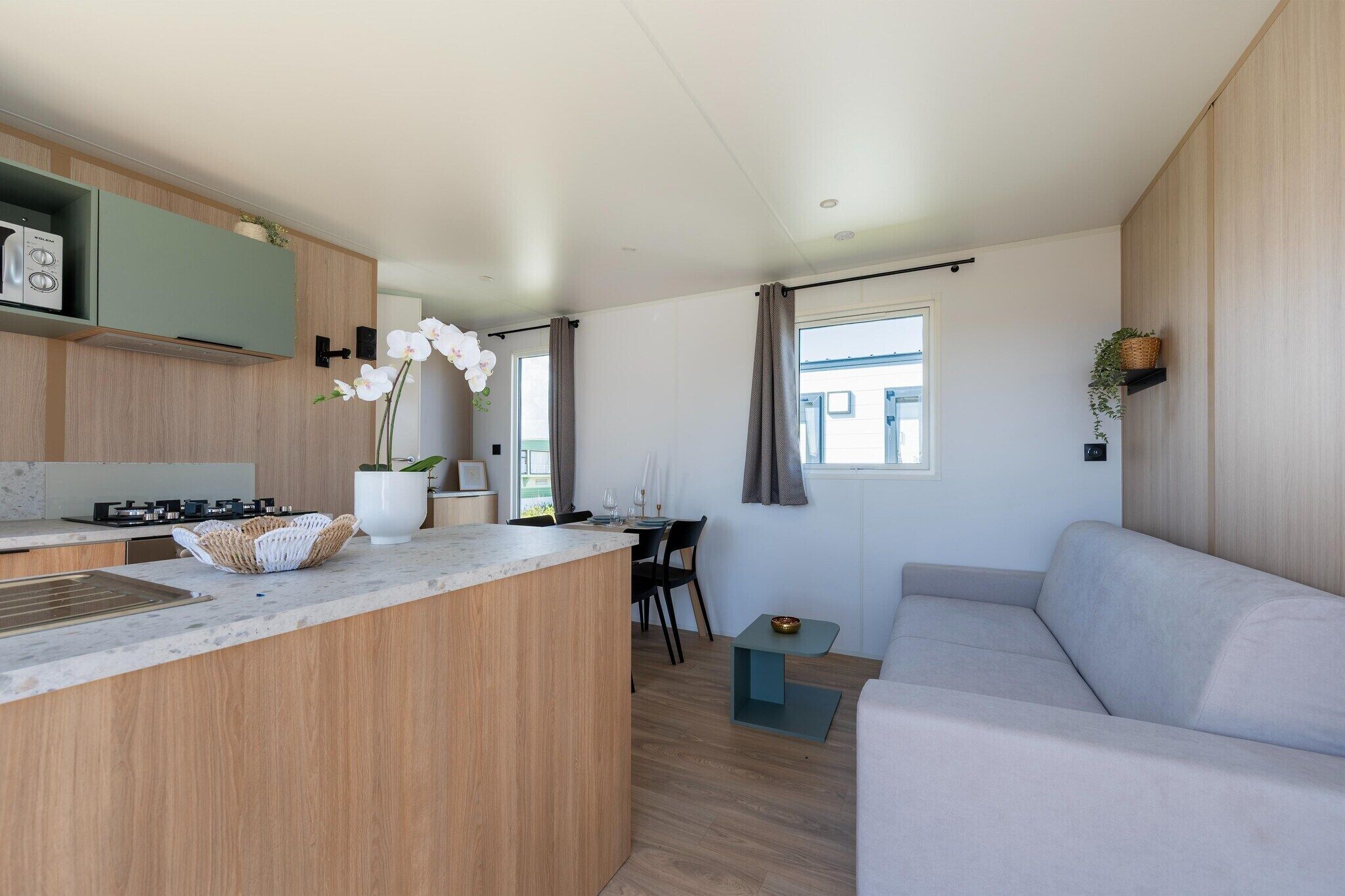 Eine moderne Küche mit einer zentralen Kochinsel, einem Essbereich mit Tisch und Stühlen sowie einem Wohnbereich mit einer Couch.