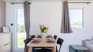Ein Essbereich mit Tisch für vier Personen, einer Blumenvase und Blick durch das Fenster.