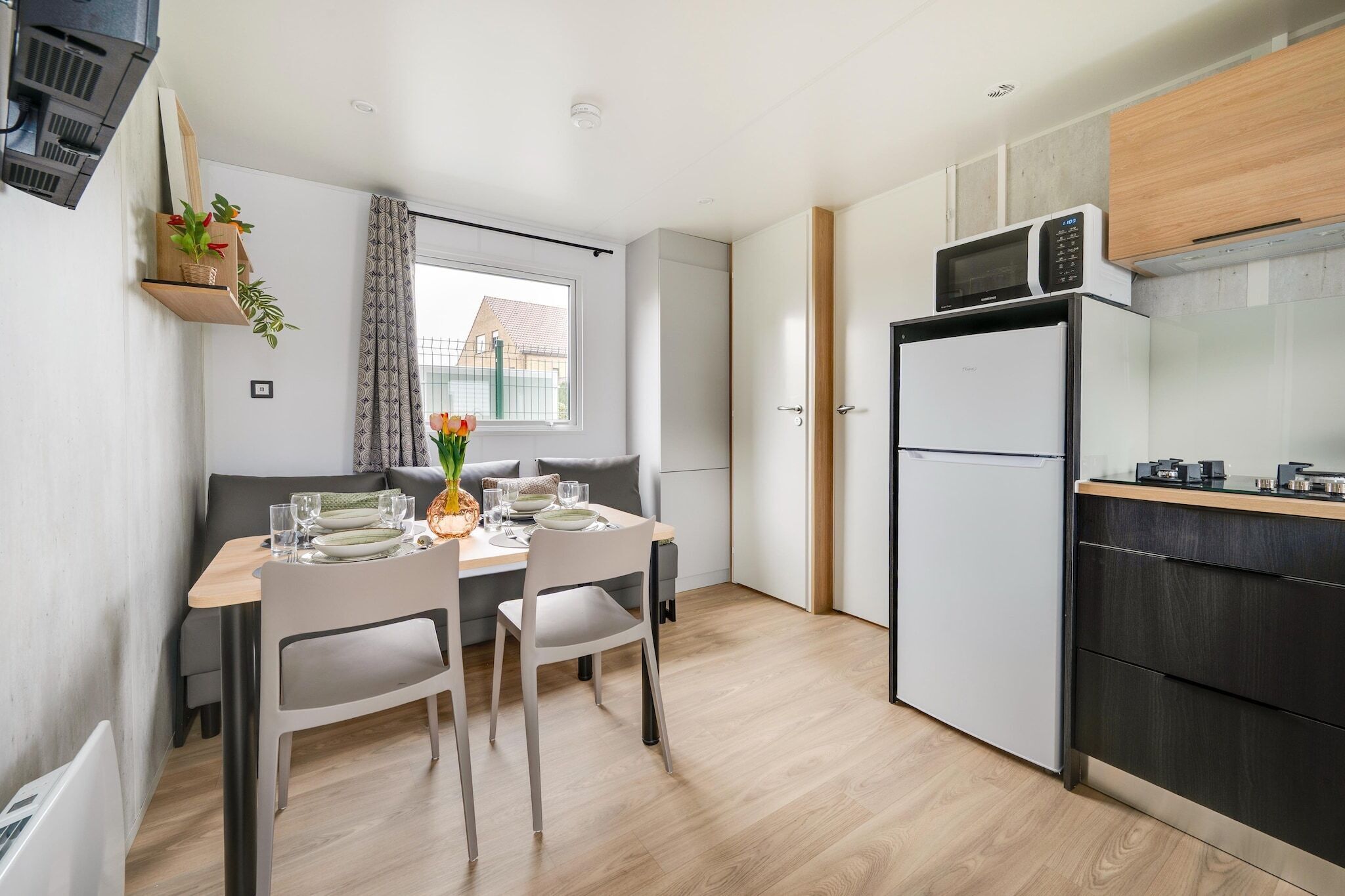 Cocina compacta con microondas, refrigerador y comedor con una mesa dispuesta para dos.